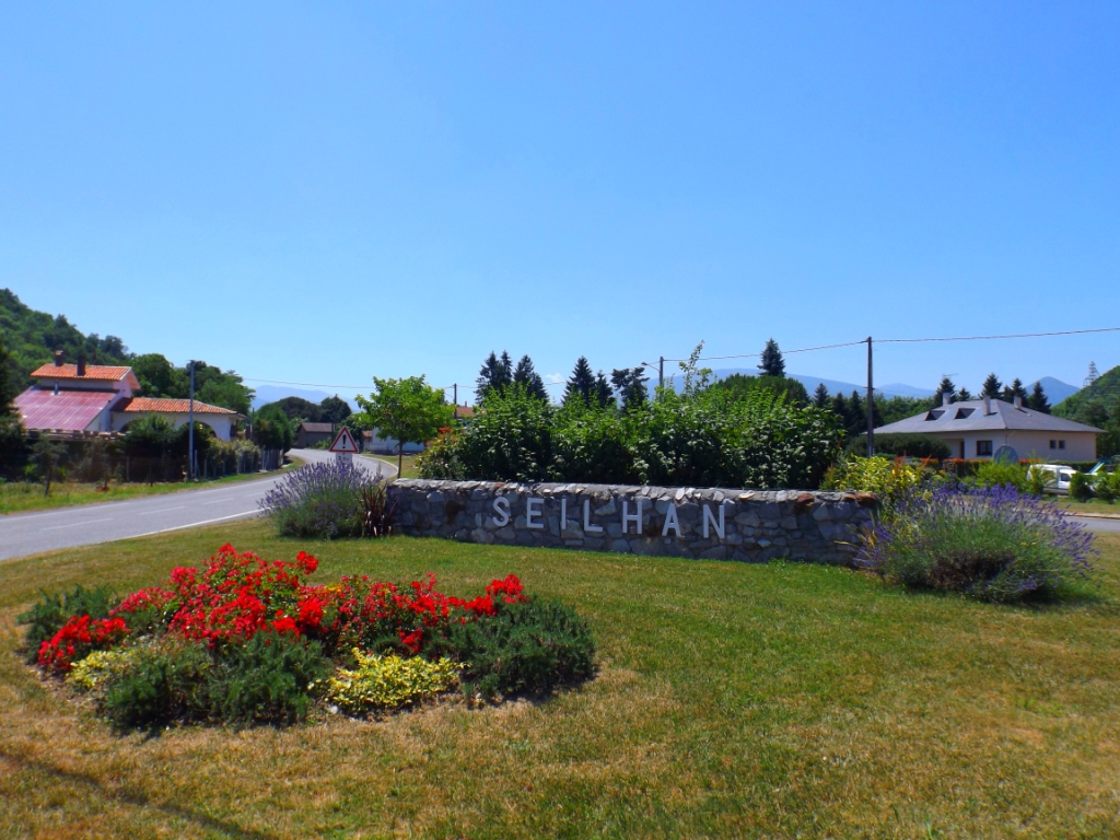 Entrée de la commune de Seilhan : massif de rosiers nains et lavande encadrant l'ancien mur